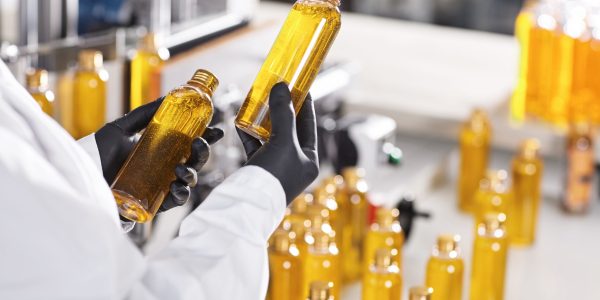 Manufacturing concept. Factory worker holding two glass bottles with yellow liquid comparing quality between them. Factory process of production shampoo. Technology, innovation and scientific concept Manufacturing concept. Factory worker holding two glass bottles with yellow liquid comparing quality between them. Factory process of production shampoo. Technology, innovation and scientific concept
